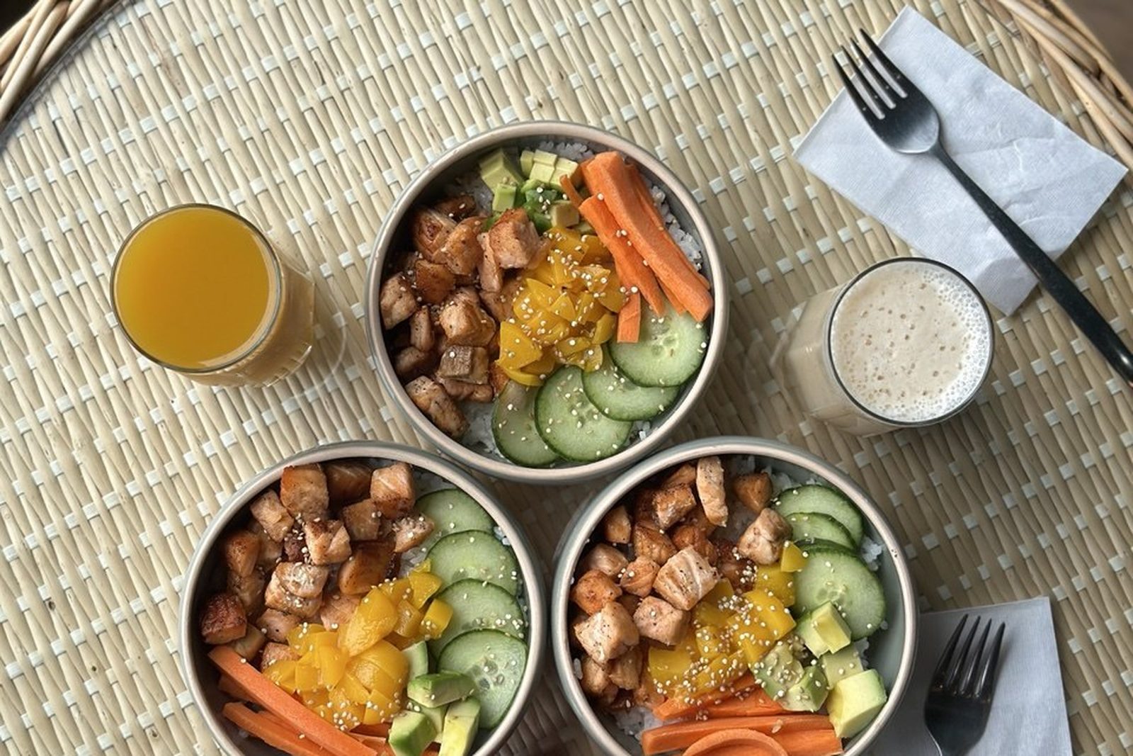 Bowls de salmón con zumo natural servidos sobre bandeja de mimbre - Dulce Néctar Gijón